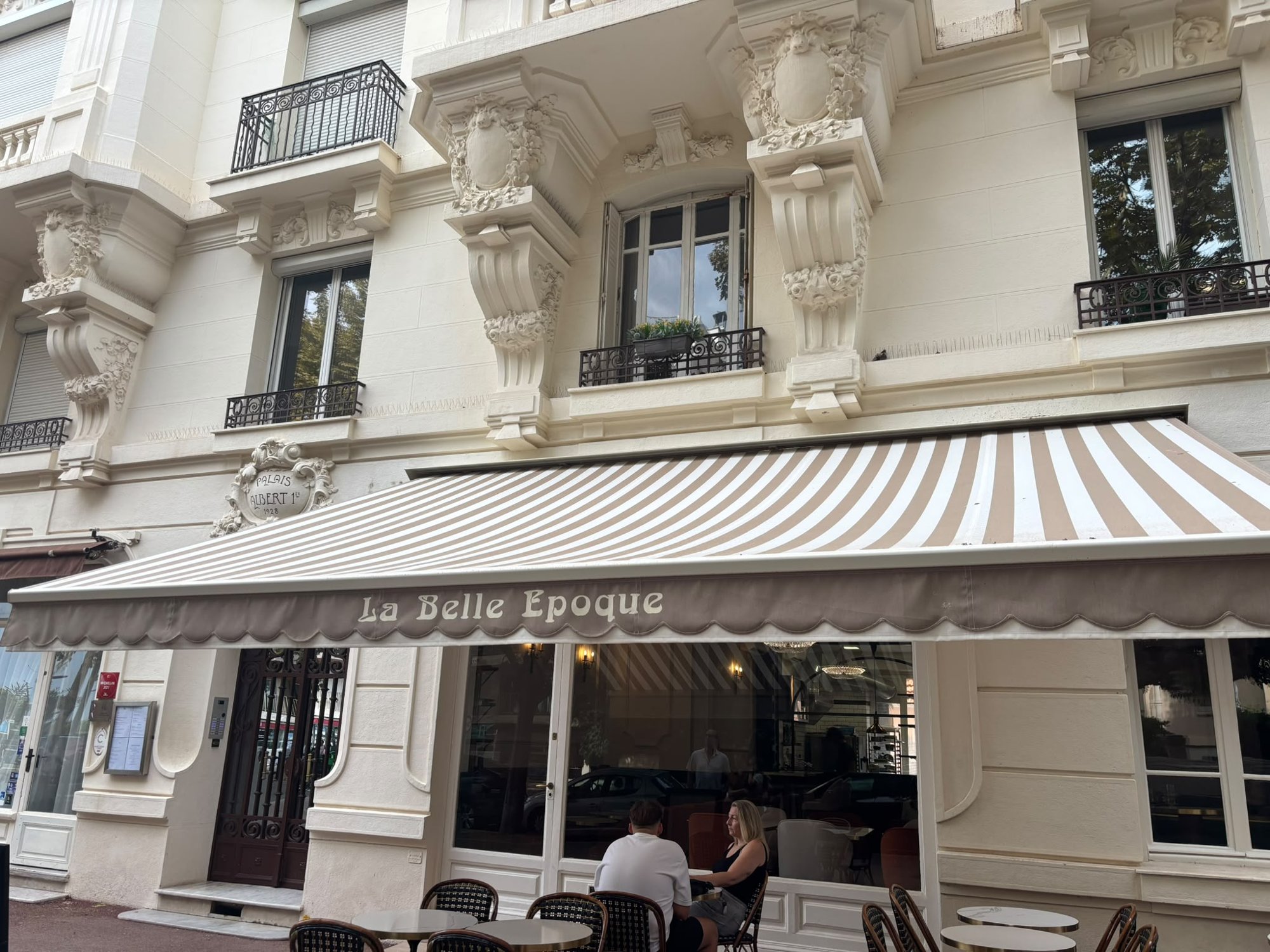La devanture de La Belle Époque sous la façade sculptée du Palais Albert 1er, avec sa terrasse