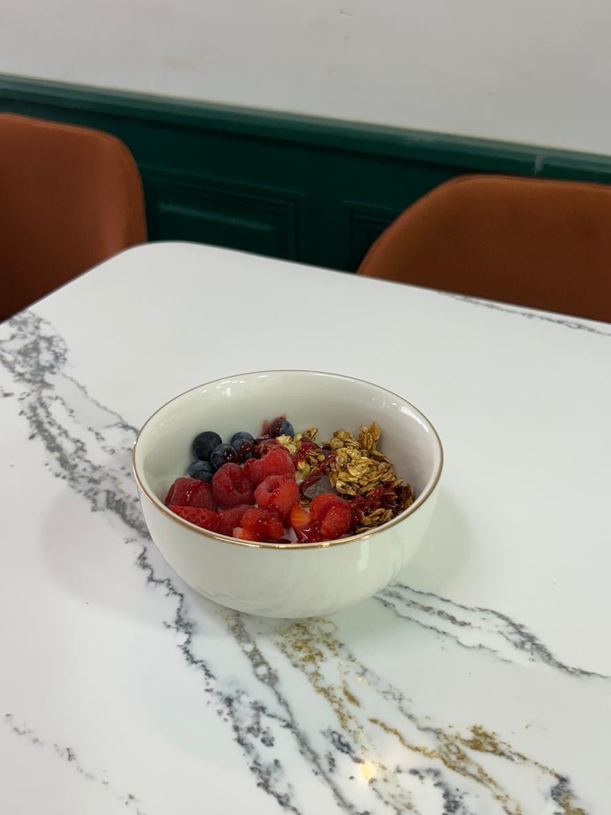 Bol de fromage blanc, granola et fruits rouges sur une table de marbre